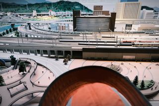 A complex model train system; the brim of a child's orange hat is visible poking out from the bottom of the frame