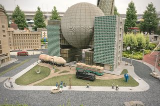 A Lego sculpture of a deathstar-like sphere held up between two skyscrapers: a model of the Nagoya science museum