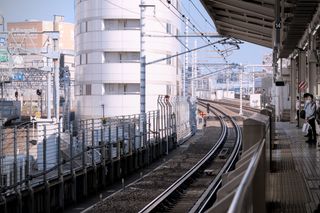 A platform next to some railroad tracks, and in the background a tall, white building and a light blue sky
