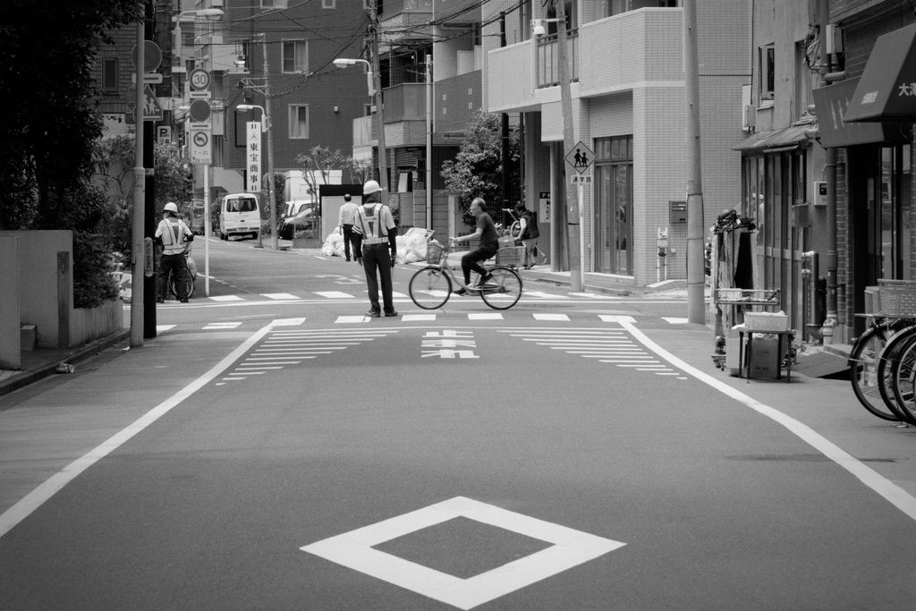 A cyclist crosses an intersection as construction workers direct traffic